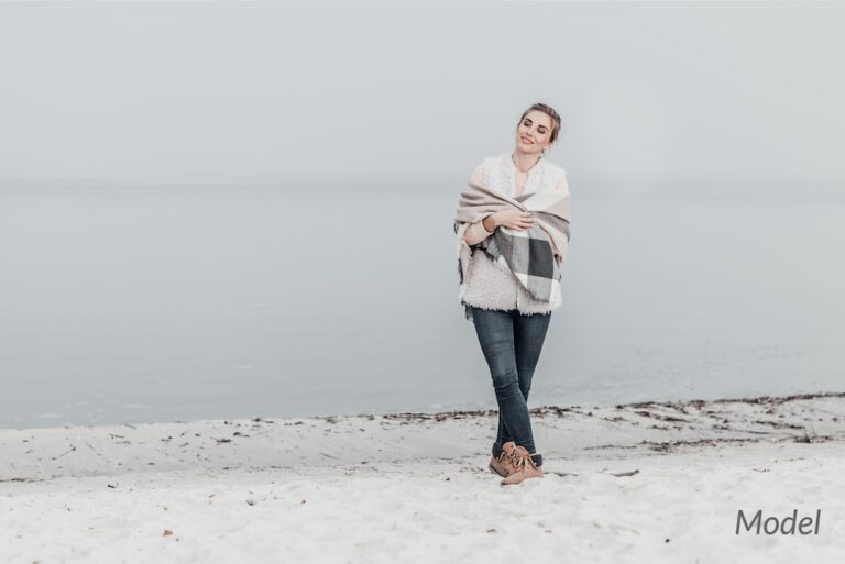 Woman standing on the beach wrapped in a blanket.